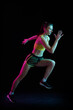 © master1305 - Professional female athlete running isolated on dark background in neon light. Healthy lifestyle, skills, sport, fitness, speed and energy concept.