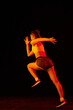 © master1305 - Professional female athlete running isolated on dark background in neon light. Healthy lifestyle, skills, sport, fitness, speed and energy concept.