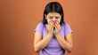 Young woman sneezing into a handkerchief because of her allergy or cold, isolated over color background