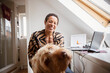 © Caia Image - Portrait happy woman with dog at desk in home office