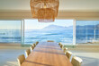 © Caia Image - Rattan pendant lights over dining table with scenic ocean view