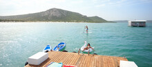 Couple Paddleboarding And Floating On Inflatable Raft On Sunny Lake
