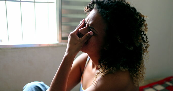 Tearful Brazilian woman crying, black latina girl in tears sitting in bed