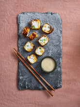 Top Angle View Of Sweet Dessert Sushi Rolls With Tropical Fruits And Delicious Coconut Dipping Sauce On Pink Background