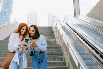 Wall Mural - Young multinational women using cellphones while standing on stairs