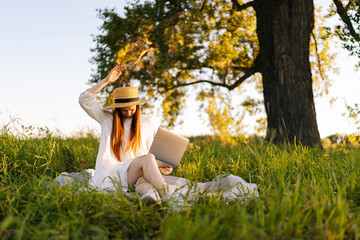 Wall Mural - dissatisfied pretty woman in straw hat and white dress chasing insects away from herself sitting on 
