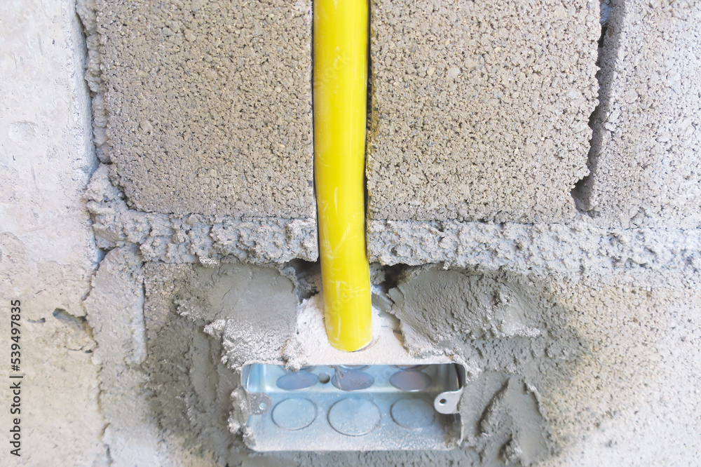 Yellow plastic PVC pipe inside building concrete wall block for embed ...