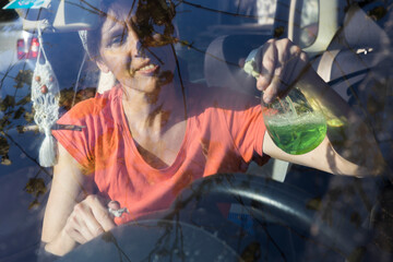 Mid Adult Caucasian Woman Cleaning Dust from Her Car Dashboard on s Sunday Morning