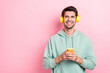 © deagreez - Photo of cheerful positive man hold telephone listen music look empty space isolated on pink color background