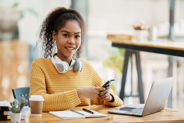 Focused young african american businesswoman or student looking at laptop holding book learning, serious black woman working or studying with computer doing research or preparing for exam online