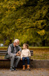 © BGStock72 - Grandfather spending time with his granddaughter on bench in park on autumn day