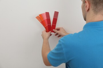 Sticker - Man with palette choosing color for painting wall indoors, closeup. Interior design