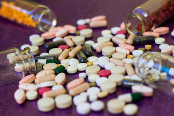 Wall Mural - Medical bottles and medication pills spilling out on to purple background