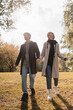 © LIGHTFIELD STUDIOS - full length of young and happy couple holding hands while walking in autumnal park.