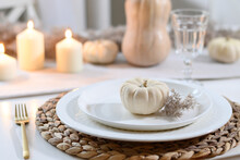Thanksgiving Day Table Setting With Candles, Fall Decorations, Centerpiece Of Dry Flowers And Pumpkin On White Table In Modern Kitchen. Close Up.
