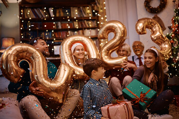 Wall Mural - Joyful multigeneration family covered with confetti's having fun while celebrating New Year at home party.