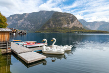 Two Swan Pedal Boats Wait For Tourists At A Small Dock On The Lake At Hallstatt, Austria.