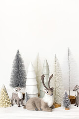 Wall Mural - Stylish little Christmas trees and reindeer toys on white background. Merry Christmas and Happy Holidays! Festive Christmas scene, miniature snowy forest. Modern nordic decorations