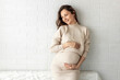 Portrait of beautiful pregnant woman in front of white wall