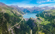 Water dam and blue reservoir lake aerial overview in Alps mountains in summer generating hydroelectricity. Low CO2 footprint, decarbonize, renewable energy, sustainable development, hydro power.