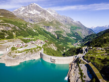 Water Dam And Reservoir Lake Aerial View In Alps Mountains Generating Hydroelectricity. Low CO2 Footprint, Decarbonize, Renewable Energy, Sustainable Development, Hydro Power. Back View.