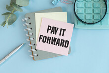 PAY IT FORWARD Text On Paper With Keyboard, Calculator On Blue Background