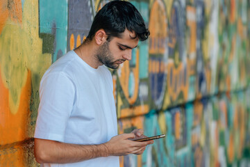 Wall Mural - young man with mobile phone in urban street