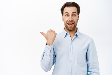 Handsome smiling businessman pointing left, showing promo or company banner aside, demonstrating advertisement, white background