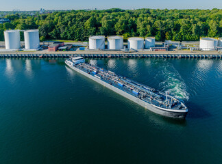 Oil tanker  sailed out from an oil storage silo terminal after unloading. Aerial view of oil tankers and storage silo tanks at a petrochemical terminal port, Kiel Canal, Holtenau.
