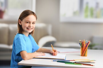 Canvas Print - Happy schoolgirl sitting at desk, classroom background