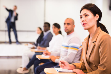 Wall Mural - Focused asian businesswoman sitting with colleagues in conference room during corporate seminar