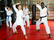 © JackF - Multiracial group of men and women in kimono performing kata in gym during training.