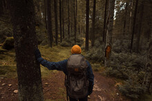 A Caucasian Man With A Backpack Hiking In The Forest Standing At A Crossroad.