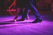© tsuguliev - Dancing shoes of a couple, couples dancing traditional latin argentinian dance milonga in the ballroom, tango salsa bachata kizomba lesson, festival on a wooden floor, purple, red and violet lights