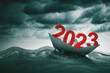 2023 number with a paper ship floating on the sea