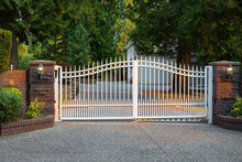 Iron Front Gate Of A Luxury Home. Wrought Iron White Gate And Brick Pillar.