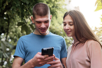 Two young friends looking at a phone, commenting on social media posts, autumn surroundings