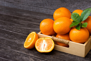 Wall Mural - Fresh orange fruit with green leaves on wooden table background.