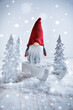 Cute Christmas gnome is sitting on sled, winter country with white trees