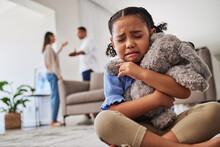 Sad, Little Girl And Crying From Parent Fight, Argument Or Divorce Hugging Teddy At Home. Unhappy Young Child In Depression, Stress And Anxiety From Mother And Father Fighting In Family Disagreement