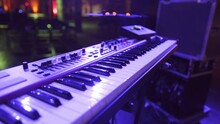 Pan Over A Digital Keyboard On An Empty Stage Under Purple Lights.