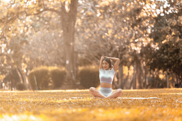 Wall Mural - Attractive Asian female in sportswear practicing yoga in the outdoor park