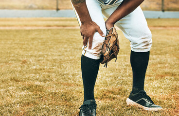 Man, baseball and sport leg injury suffering in pain, agony and discomfort during training match or game on the field. Male athlete hurt holding painful area in sports accident on grass or pitch