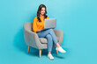 © deagreez - Full size photo of pretty positive girl sit use netbook write typing email isolated on blue color background