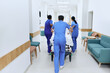 © Peakstock - Hospital care team wheeling patient on medical gurney at emergency department of hospital, back view