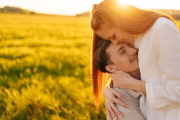 Wall Mural - portrait of loving young couple standing gentle hugging with closed eyes on green meadow in summer e