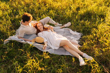 Wall Mural - high-angle view of happy young woman lying of handsome man during romantic picnic in nature, on back