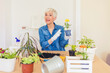 © Jelena Stanojkovic - Happy female caring for house plant. Woman taking care of plants at her home, spraying a plant with pure water from a spray bottle