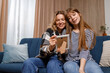 © Andrii  - Happy mother and daughter looking at photo frame sitting on sofa at home