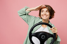 Young Smiling Happy Cool Woman 20s She Wear Green Shirt White T-shirt Hold Steering Wheel Driving Car Look Aside Hold Hand At Forehead Isolated On Plain Pastel Light Pink Background Studio Portrait.